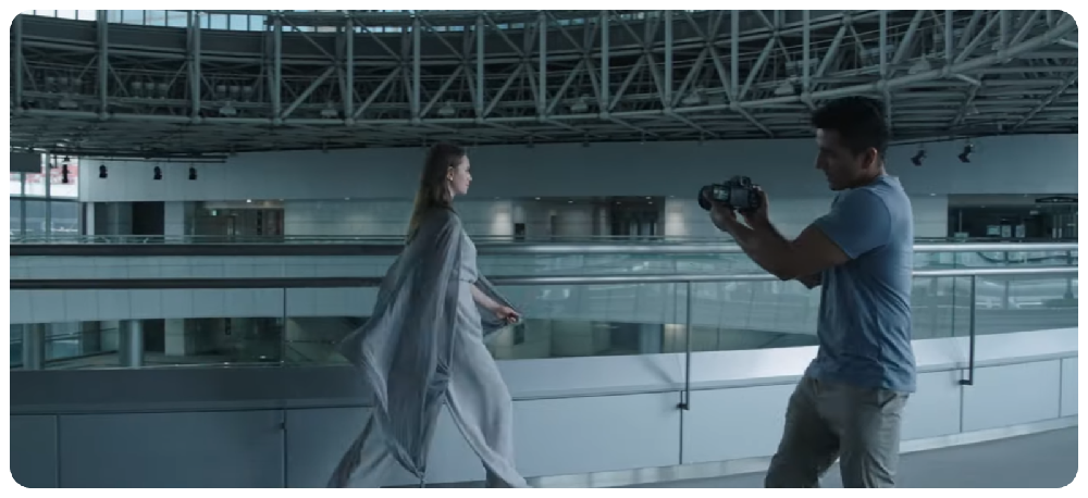 Sony A7 IV used by filmmaker recording woman walking through modern glass architecture building